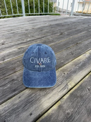 Blå denimkeps från Civare - Säljer en snygg blå keps från Civare med broderad text 'CIVARE EST. 2026' framtill. Kepsen är i tvättad denim-look och har klassisk böjd skärm. Perfekt accessoar för en avslappnad streetwear-stil.