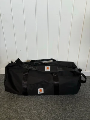 Carhartt Duffel Bag / Weekendbag – Svart – Bra skick - Carhartt duffel/weekendbag i svart. Bra skick utan defekter. Köpt second hand men knappt använd av mig. Rymlig och perfekt till gym/resor/weekend. Fraktar via PostNord 📦
