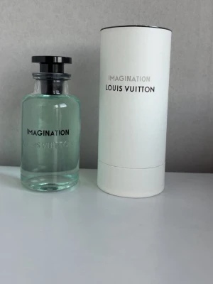 Louis Vuitton Imagination parfym - Lyxig parfym från Louis Vuitton i doften Imagination. Flaskan är genomskinlig med ljusblått innehåll och har en svart rund kork. Kommer i en stilren vit cylinderformad förpackning med silverdetaljer. Perfekt för dig som gillar exklusiva dofter.