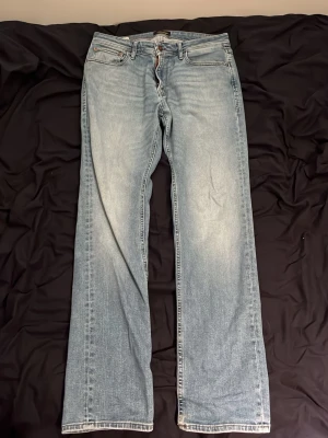Ljusblå raka jeans från Jack and Jones - Ljusblå jeans från Jack and Jones med klassisk femficksdesign och raka ben. Jeansen har en snygg tvättad look och är tillverkade i bomull. Perfekta för en avslappnad och trendig stil.