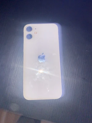 Vit iPhone 12 med dubbla kameror - Snygg vit iPhone 12 med stilren design och rundade hörn. Baksidan är i glas och har två kameror samt Apple-loggan i mitten. Sidorna är i aluminium och mobilen har en modern look som passar perfekt för dig som gillar Apple.