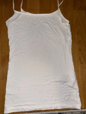 Vit linnetopp från Esprit - Säljer en enkel och stilren vit linnetopp från Esprit med tunna axelband. Toppen är rak i modellen och gjord i mjuk bomull, perfekt att matcha till olika outfits. Klassisk basic som alltid funkar.