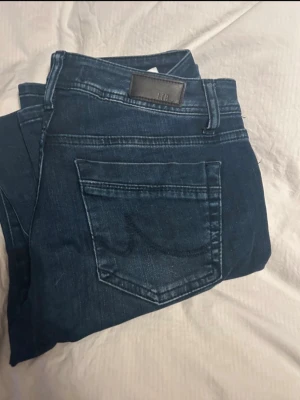 Mörkblå jeans LTB - Snygga mörkblå jeans från LTB med klassisk femficksdesign och raka ben. Jeansen har en diskret läderpatch bak i midjan och kontrastsömmar som ger en stilren look. Perfekta till en avslappnad outfit.