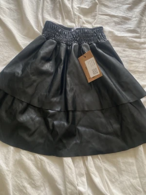 Kjol - Svart kjol i skinn imitation. Aldrig använd. Köpt på sellpy men är från subdued