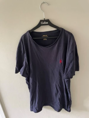 Mörkblå t-shirt från Polo Ralph Lauren - Snygg mörkblå t-shirt från Polo Ralph Lauren med klassisk röd logga broderad på bröstet. T-shirten har rund halsringning och korta ärmar. Tillverkad i mjuk bomull som är skön att bära.