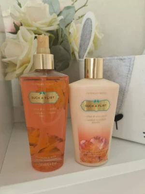 Victoria's Secret Such A Flirt duo - Säljer ett set med Victoria's Secret Such A Flirt body mist och body lotion. Mist i genomskinlig orange plastflaska med guldfärgad spray och lotion i ljusbeige plastflaska med guldfärgat lock. Båda doftar starfruit & white orchid. 250 ml vardera. Knappt använt. Säljer nu av min vintage kollektion. Perfekt för samlare. Eftersom dofterna är vintage kan lukten skilja sig markant från nya, och köps därmed på eget bevåg.