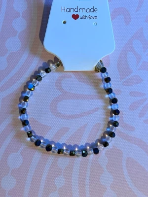 Handgjort armband med pärlor - Snyggt handgjort armband med små runda pärlor i svart och transparent. Pärlorna är glansiga och sitter på en elastisk tråd. Perfekt accessoar för att ge din stil en personlig touch.