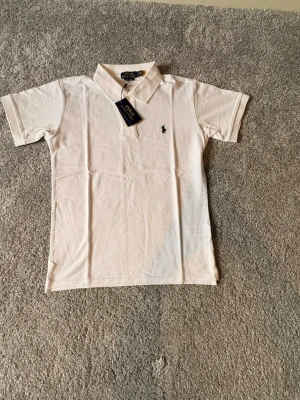 Ralph lauren piké Ny-oanvänd (s) -  Säljer en helt ny och oanvänd Ralph Lauren piké i storlek S. Klassisk och stilren design i vit färg med broderad Ralph Lauren-logga på bröstet. Pikén är tillverkad i hög kvalitet med bekvämt och luftigt material – perfekt för både vardag och en mer uppklädd look. 🔹 Märke: Ralph Lauren 🔹 Modell: Piké 🔹 Färg: Vit 🔹 Storlek: S 🔹 Skick: Helt ny / oanvänd 🔹 Passform: Klassisk Nypris är högt – perfekt chans att göra ett fynd. Hör gärna av dig vid funderingar  