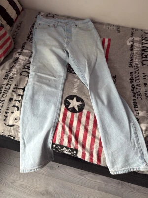 Ljusblå raka Levi's jeans - Säljer ett par klassiska ljusblå Levi's jeans med rak passform och fem fickor. Jeansen har en vintage vibe och är tillverkade i slitstark denim. Perfekta för dig som gillar en avslappnad och tidlös stil. Den har en väldigt liten fläck på botten av jeansen som knappt syns och går enkelt bort i en tvätt. PRIS KAN DISKUTERAS.