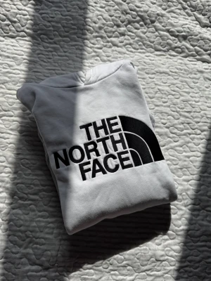 Vit hoodie från The North Face - Snygg vit hoodie från The North Face med stor svart logga på bröstet. Storlek youth xl som motsvarar ålder 14-17