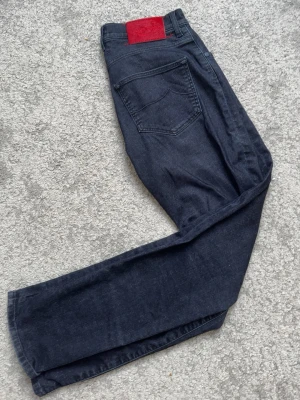Jacob cohen jeans mörkblåa - Snygga mörkblå jeans från Jacob Cohen med klassisk femficksdesign och röd patch bak i midjan. Jeansen har raka ben och är tillverkade i denim. Perfekta för en avslappnad och trendig look. Längd: 95cm midja: 35cm