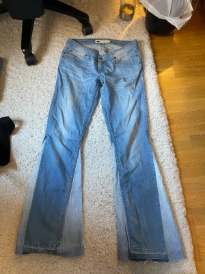 Ljusblå flared jeans från Levi's - Säljer ett par ljusblå flared jeans från Levi's med klassisk femficksdesign och snygga kontrastsömmar. Jeansen har en låg midja och utsvängda ben, perfekt för en avslappnad och trendig look. Ikonisk Levi's-logga på bakfickan. Custom made btw 🤩