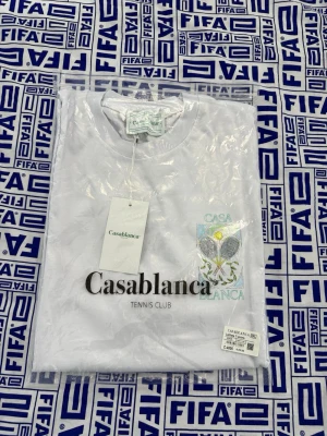 Vit Casablanca Tennis Club t-shirt - Vit t-shirt från Casablanca med tryck 'Tennis Club' och ett färgglatt tennisinspirerat motiv på bröstet. Klassisk rund hals och korta ärmar. Perfekt för en sportig och trendig look. Storlek XXL men passar XL 