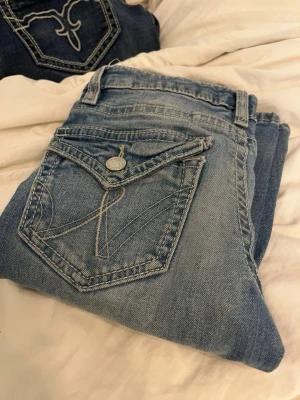 Ljusblå jeans från Gina Tricot Young - Snygga ljusblå jeans från Gina Tricot Young med coola detaljer på bakfickan och klassisk femficksmodell. Jeansen har en avslappnad passform och är tillverkade i mjukt denimtyg. Perfekta för en trendig vardagslook.