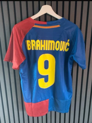 FC Barcelona Ibrahimović tröja - Säljer en klassisk FC Barcelona matchtröja från Nike med Ibrahimović och nummer 9 på ryggen. Tröjan är blå och röd med gula detaljer, klubbmärke och Unicef-logga på bröstet. Perfekt för dig som älskar fotboll och vill ha en ikonisk supportertröja.
