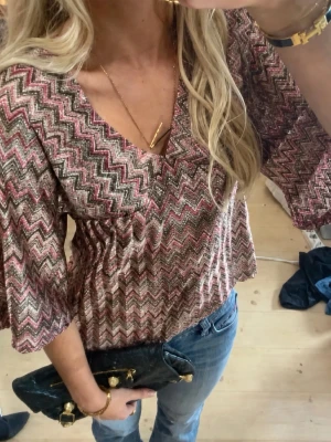 Missoni blus med v-ringning -  LÅNAD BILD!Säljer en snygg blus med zickzack-mönster i rosa. Blusen har v-ringning, trekvartsärmar och en lös passform. Den har storlek S, men passar som xs också.