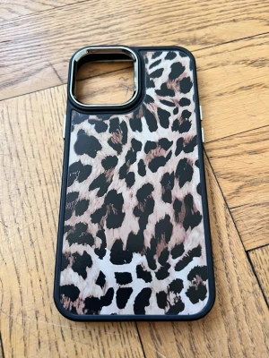 Mobilskal med leopardmönster - Snyggt mobilskal med leopardmönster i svart, beige och brunt. Skalets kanter är svarta och det har en förstärkt ram runt kameran. Perfekt för dig som vill ha ett trendigt och djurinspirerat mobilskal.