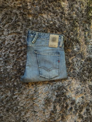 Replay Anabass - Blå slim fit jeans från Replay. 32/32 midja 43cm ytterbenlängd 103cm. Modellen är 72kg 183cm. Hål i skrevet(se sista bild)