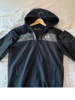 Svart under armor vindjacka - Säljer nu denna sjukt feta under armor vindjacka i storlek S, den har inga defekter och jag säljer den för att den är lite stor för mig, skriv till mig om ni har några frågor eller funderingar 🙌🤩🍾