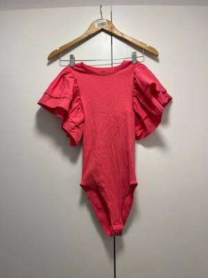 Rosa volangbody från Zara - Supersnygg rosa body från Zara med stora volangärmar som ger en statement-look. Knapparna sitter inte bra nog så har aldrig använt som en body, kan lätt fixas vid att byta ut knapparna
