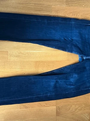 Mörkblå jeans Dressmann - Snygga mörkblå jeans från Dressmann. Klassisk femficksmodell med kontrastsömmar och rak passform. Perfekta till vardagslooken och tillverkade i mjukt denimtyg för skön känsla.
