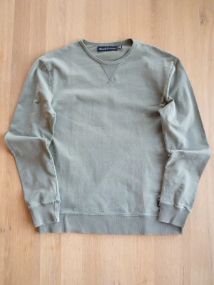 Olivgrön sweatshirt från Deus Ex Machina - Snygg olivgrön sweatshirt från Deus ex machina med rund halsringning och ribbade muddar vid ärmslut och nederkant. Tröjan har en klassisk relaxed fit och är tillverkad i mjuk bomull. Perfekt för en avslappnad och stilren look.