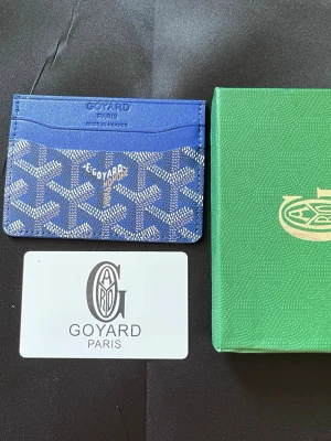 Blå korthållare  - Snygg blå korthållare med det klassiska vita och gråa. Tillverkad i canvas och läder, har flera kortfack och präglad logotyp framtill. Perfekt för dig som vill ha en exklusiv och stilren accessoar från Paris.