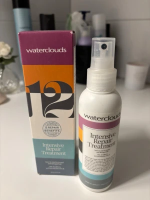 Waterclouds Intensive Repair Treatment - Intensiv hårbehandling från Waterclouds i sprayflaska. Produkten är vit med färgglad etikett i lila, orange och turkos. Ger 12 reparerande fördelar för håret och passar perfekt för dig som vill stärka och vårda skadat hår.