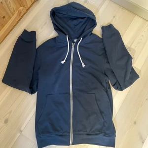 ZIP-HOODIE | PIER ONE. - Snygg mörkblå hoodie med dragkedja framtill och vita dragsnören i huvan. Klassisk känguruficka på magen och ribbade muddar vid ärmar och nederkant. Perfekt för en avslappnad och cool stil.