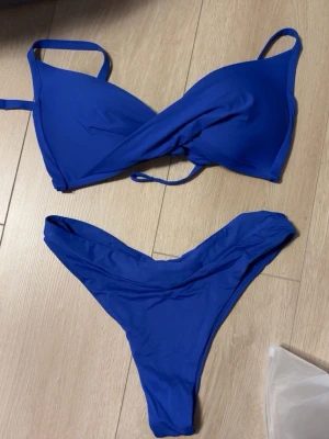 Blå omlott bikini  - Snygg blå bikini från calzedonia med omlott-topp och smala axelband. Underdelen har hög midja och V-formad skärning framtill. Storlek S. 