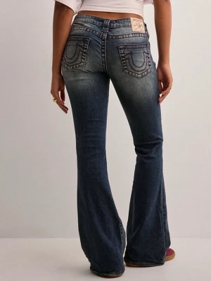 Jeans från True Religion - Säljer ett par blå bootcut jeans från True Religion med klassiska kontrastsömmar och broderade bakfickor. Ända defekten är på sista bilden, lite slitet längst ner på ena benet. Innerbenslängd 80 cm
