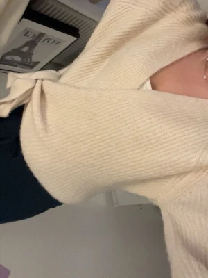 Beige omlottstickad tröja - Säljer en beige stickad omlott-tröja med knytband i beige.🤍 Jag säljer eftersom den inte kommer till användning.