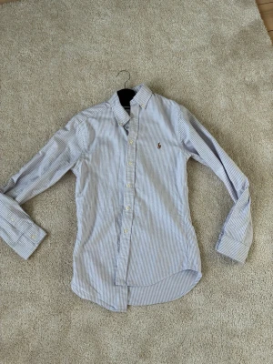 Randig skjorta från Polo Ralph Lauren - Säljer en snygg randig skorjta från Ralph lauren. Skick 9,5/10 använd 3 gånger.storlek xs och är slimfit. Hör av er vid funderingar