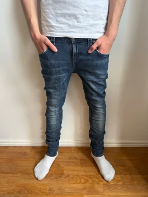 Blå slim fit jeans från Nudie Jeans - Säljer ett par blå slim fit jeans från Nudie Jeans med klassisk femficksmodell och snygga slitningar på knän och lår. Jeansen har en smal passform och är tillverkade i stretchig denim för extra komfort. Perfekta för en avslappnad och trendig look. Strl: W30 L32✅ Pris kan diskuteras!💸 Hör av dig om du har funderingar!👍