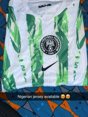 Nigeria fotbollströja Nike - Säljer en officiell Nigeria fotbollströja från Nike med grönt och vitt mönster och Nigeria Football Federation-logga på bröstet. Tröjan har rund hals och är tillverkad i ett lätt, ventilerande material perfekt för träning eller match.