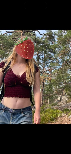 Vinröd croppad topp med puffärm - Säljer en vinröd croppad topp med puffärmar och smockad midja. Toppen har en v-ringad halsringning med snörningsdetalj och små volanger i nederkant. Perfekt för dig som gillar en feminin och trendig stil.