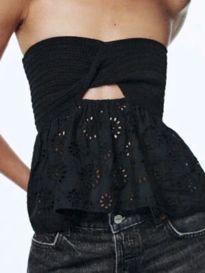 Svart axelbandslös topp från Zara - Snygg svart axelbandslös topp från Zara med twistad bandeau upptill och broderade blommor på den utsvängda nederdelen. Aldrig använd och i nytt skick! 