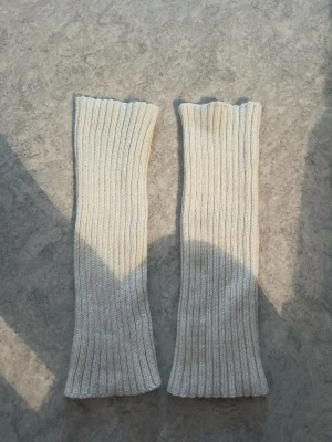 Långa ribbade benvärmare i ullmix - Säljer ett par långa, ribbade benvärmare i ljusbeige färg. De är stickade och har en mjuk och stretchig känsla, perfekta att dra över leggings eller jeans för extra värme. Passar till dig som vill ha en enkel men snygg detalj till din outfit. Nypris 28kr. Använd fåtal gånger utan defekter
