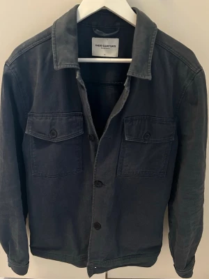 Mörkblå Overshirt These Glory Days - En jäkligt schysst overshirt från These Glory Days. En fin mörkblå färg, man kan ha den över en hoodie eller bara över en T-shirt. Skönt plagg att ha nu under sommaren. Väldigt bra skick! Storlek:M