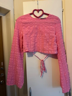 Gina tricot topp rosa strl XS - Topp med långa ärmar och fyrkantigt texturerat mönster. Toppen har en rund halsringning och snörning baktill.