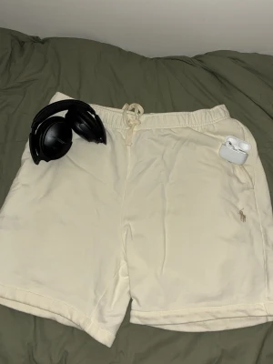 Beige shorts från Polo Ralph Lauren - Snygga beige shorts från Polo Ralph Lauren med klassisk broderad logga på benet. De har snörning i midjan och är tillverkade i mjuk bomull, perfekta för chill dagar. Enkel och stilren design som passar till det mesta. Passar perfekt med en kortärmad skjorta. 👔. Om ni har några funderingar för dessa nya stilrena shorts så skriv till mig.🙌 storleken är large men passar även medium.