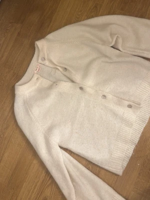 Krämvit kofta från Gina Tricot - Jättefin krämvit stickad kofta med knappar ifrån Gina Tricot. Knappt använd och i jättebra skick. I storlek 158/164