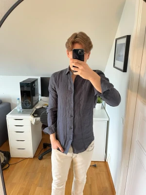 Mörkblå linneskjorta med knappar från Riley - Snygg mörkblå skjorta i 100% linne med klassisk krage och knäppning framtill. Det följer även med 2 extra knappar. Hör gärna av dig vid frågor!