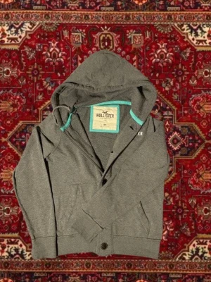 Hollister cardigan med luva! - Säljer denna feta hollister cardiganen/hoodien! | Storlek M | Mycket bra skick | Längd ≈ 64cm | Bredd ≈ 50cm | Passar 175cm - 185cm | Hör av dig vid fler frågor!