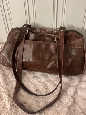 Snygg brun äkta läderväska - Brun läderväska med silver detaljering axelremmar från the monte, lite sliten. Skriv för mer frågor☺️