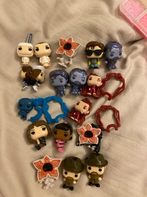 Stranger Things samlarfigurer mix - Säljer ett gäng små samlarfigurer från Stranger Things, inklusive flera karaktärer och monster i olika färger och former. Figurerna är tillverkade i plast och har detaljerade ansikten och kläder. Perfekt för dig som gillar serien och vill ha coola prylar att ställa upp.