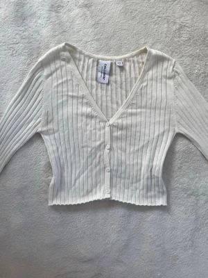 Krämvita stickad kofta  - Krämvit kortare stickad kofta med knappar från Collusion i storlek M. 