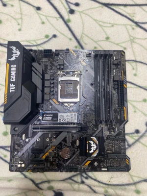 ASUS TUF Gaming moderkort svart/gul - ASUS TUF Gaming moderkort i svart med gula detaljer. Moderkortet har flera RAM-platser, PCIe-portar och M.2 SSD installerad från Kingston. Robust design med TUF Gaming-logga och kylflänsar. Perfekt för gamingbyggen och kraftfulla datorer.