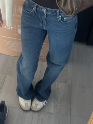 NA-KD low waist jeans  - Säljer ett par klassiska blå raka jeans med låg midja och raka ben. Jeansen har fem fickor och stängs med knapp och dragkedja. Perfekta till sneakers eller boots för en avslappnad look.