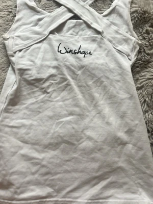 Vit linnetopp från Winshape - Snygg vit linnetopp från Winshape med korsade axelband i ryggen.💓